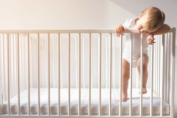 Baby on the side of a crib railing